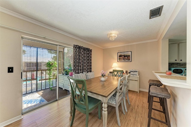 dining area with washer / clothes dryer, ornamental molding, a textured ceiling, and light wood-type flooring