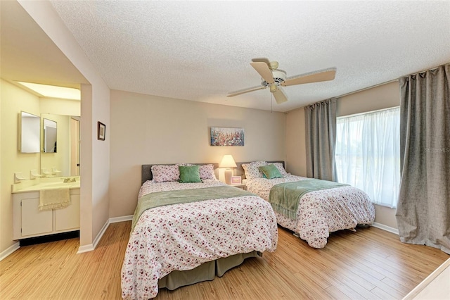 bedroom with ceiling fan, light hardwood / wood-style flooring, ensuite bathroom, and a textured ceiling