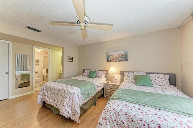 bedroom with a textured ceiling, ceiling fan, light hardwood / wood-style floors, and ensuite bathroom