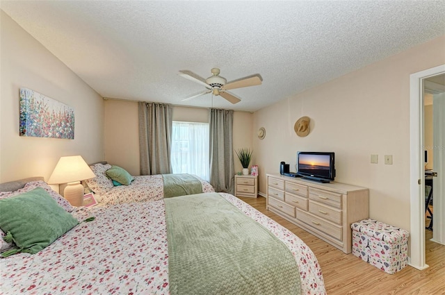 bedroom featuring ceiling fan, light hardwood / wood-style flooring, and a textured ceiling