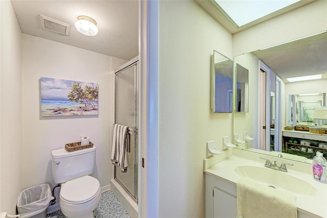 bathroom with vanity, a skylight, toilet, and a shower with door