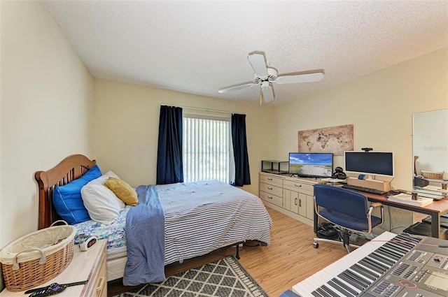 bedroom with ceiling fan, light wood-type flooring, and a textured ceiling