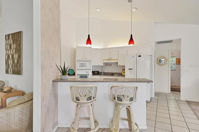 kitchen with pendant lighting, white appliances, kitchen peninsula, vaulted ceiling, and white cabinetry