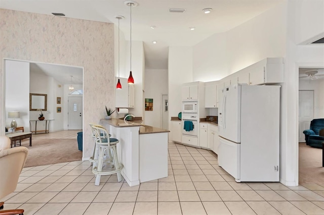 kitchen with white cabinets, white appliances, light carpet, and a high ceiling