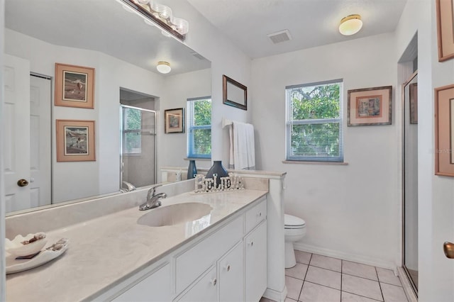 bathroom with tile patterned floors, vanity, toilet, and a wealth of natural light