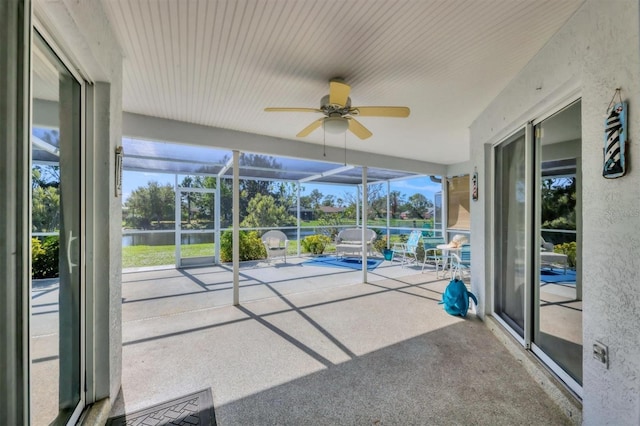 unfurnished sunroom with ceiling fan, plenty of natural light, and a water view