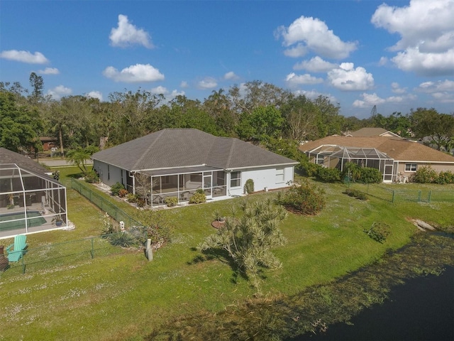 back of property with glass enclosure and a yard