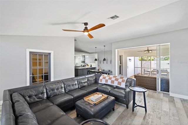 living room with ceiling fan, light wood-type flooring, and lofted ceiling