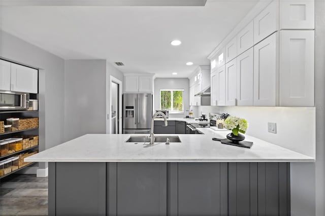 kitchen with sink, stainless steel appliances, dark hardwood / wood-style flooring, kitchen peninsula, and white cabinets