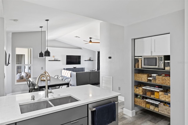 kitchen with pendant lighting, gray cabinetry, lofted ceiling, sink, and appliances with stainless steel finishes