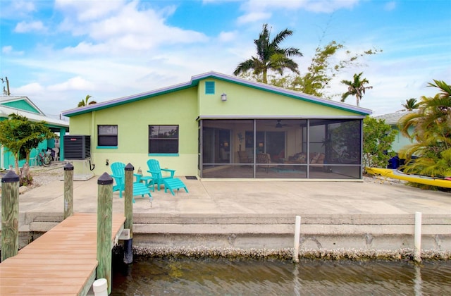 back of property featuring central AC unit, a patio area, a sunroom, and a water view