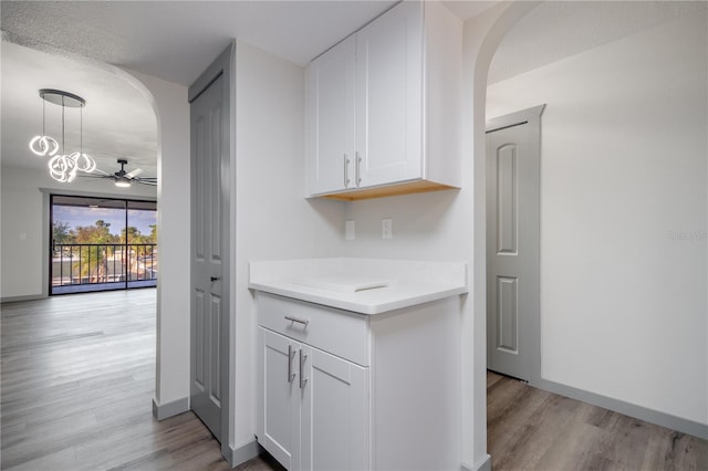 kitchen featuring light hardwood / wood-style floors, a textured ceiling, ceiling fan, white cabinetry, and decorative light fixtures