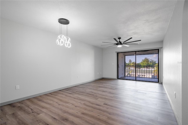 empty room with ceiling fan, a textured ceiling, and light wood-type flooring