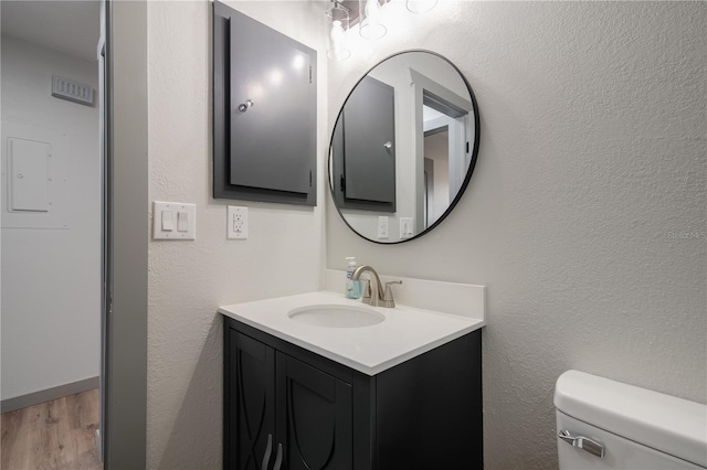 bathroom with toilet, vanity, and wood-type flooring