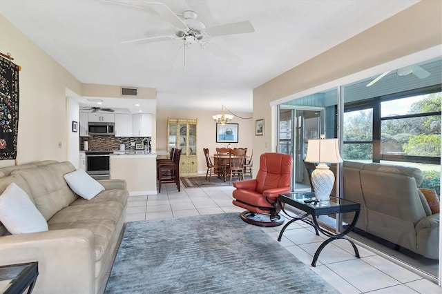 tiled living room featuring ceiling fan with notable chandelier