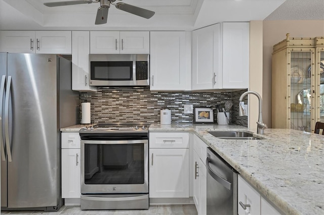 kitchen featuring sink, stainless steel appliances, tasteful backsplash, light stone counters, and white cabinets