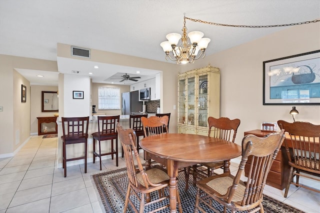 tiled dining room featuring ceiling fan with notable chandelier