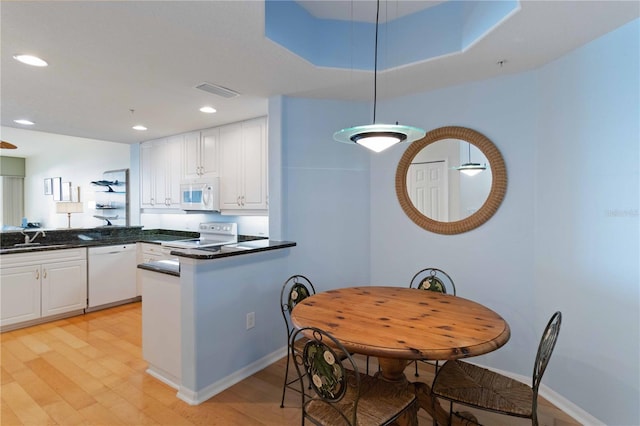 kitchen featuring kitchen peninsula, light wood-type flooring, white appliances, and white cabinetry