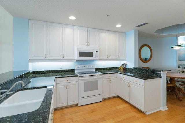 kitchen with light hardwood / wood-style flooring, white appliances, kitchen peninsula, and white cabinets