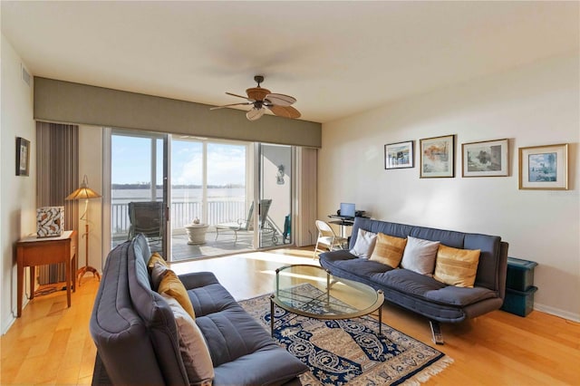 living room with ceiling fan, light hardwood / wood-style flooring, and a water view