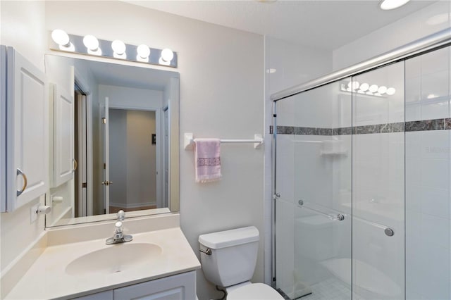 bathroom featuring vanity, a shower with shower door, and toilet