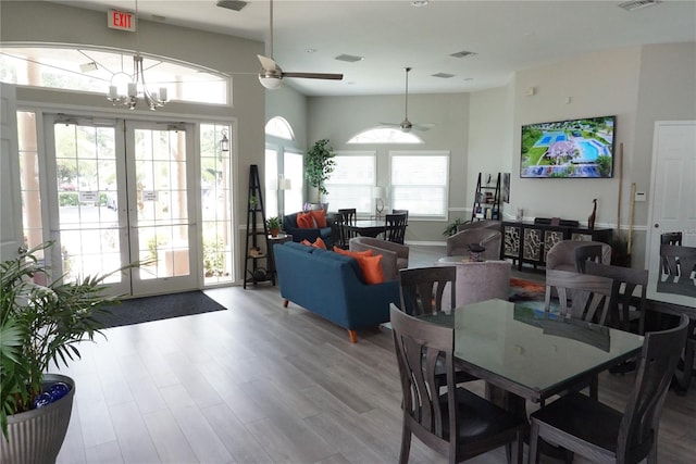 dining room with french doors, ceiling fan with notable chandelier, and light wood-type flooring