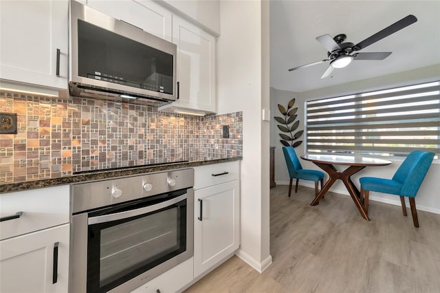 kitchen with white cabinets, appliances with stainless steel finishes, and dark stone counters