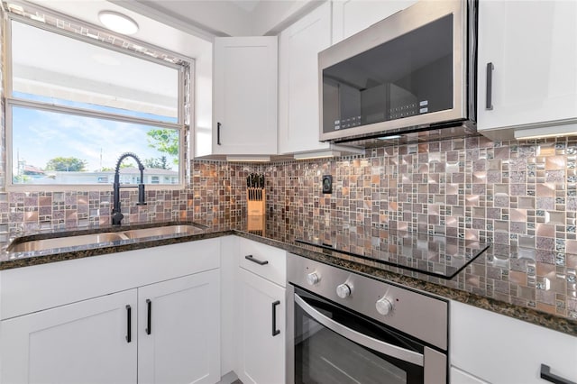 kitchen with decorative backsplash, sink, white cabinets, and appliances with stainless steel finishes