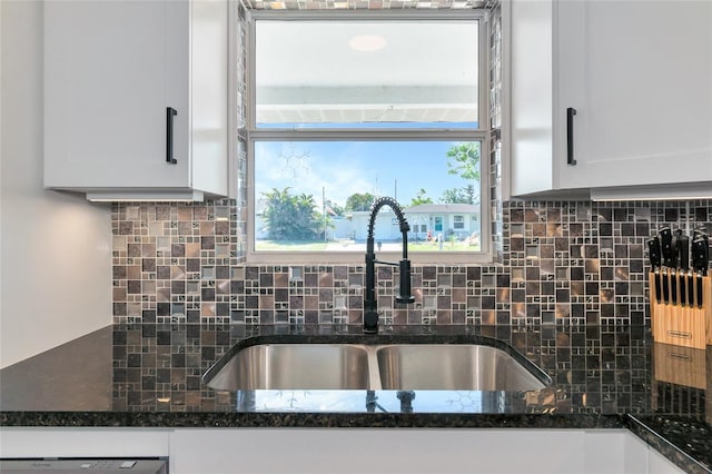 kitchen with dark stone countertops, sink, and white cabinets