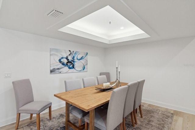 dining area with a tray ceiling and hardwood / wood-style floors