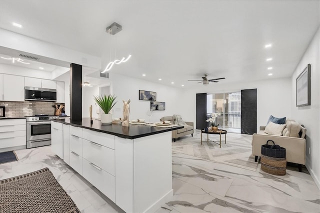 kitchen featuring backsplash, hanging light fixtures, ceiling fan, appliances with stainless steel finishes, and white cabinetry