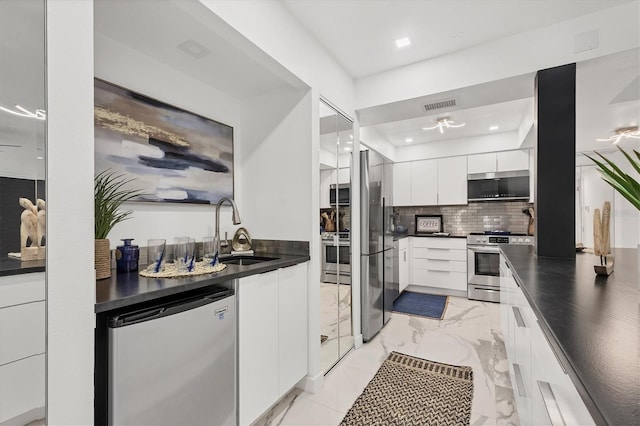 kitchen with white cabinets, stainless steel appliances, tasteful backsplash, and sink