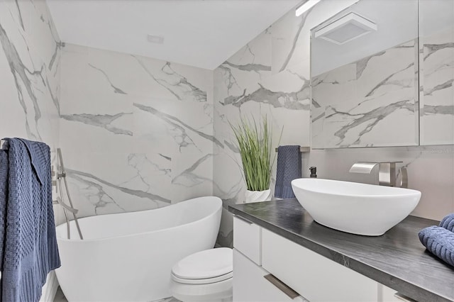 bathroom featuring a bathing tub, vanity, toilet, and tile walls