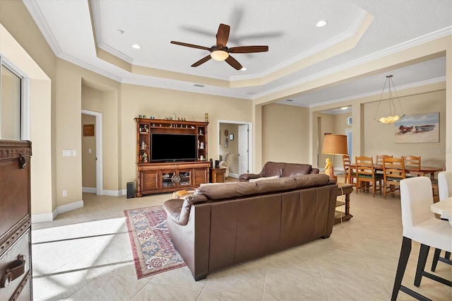 living room with a tray ceiling, crown molding, and ceiling fan