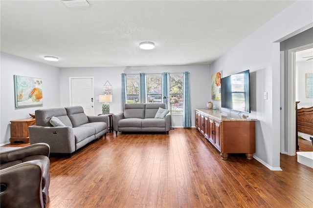 living room with a textured ceiling and dark hardwood / wood-style floors