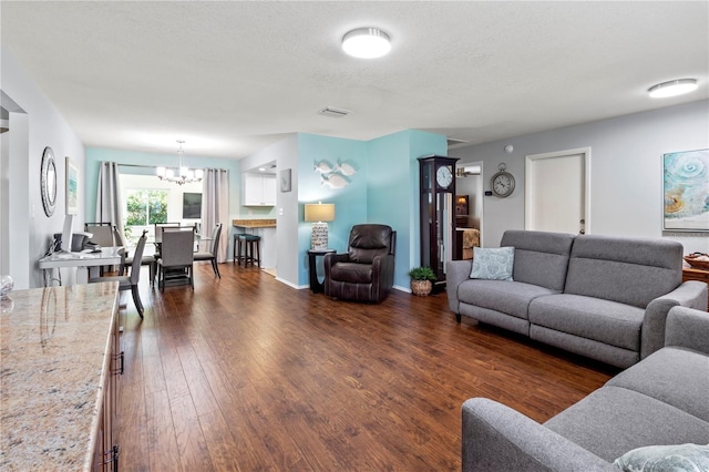 living room with a chandelier, a textured ceiling, and dark wood-type flooring