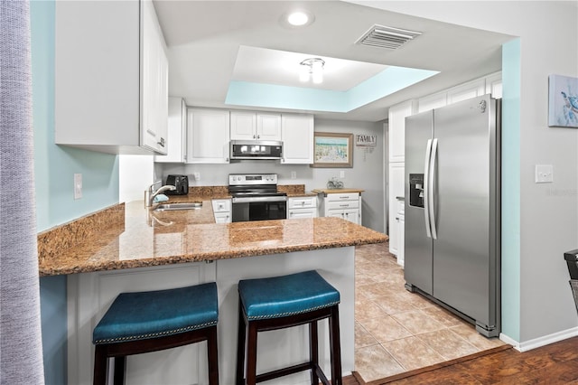 kitchen with white cabinetry, sink, light hardwood / wood-style flooring, kitchen peninsula, and appliances with stainless steel finishes