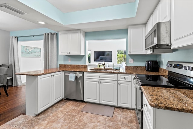 kitchen with kitchen peninsula, appliances with stainless steel finishes, sink, light hardwood / wood-style flooring, and white cabinets