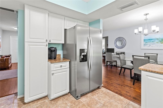 kitchen featuring pendant lighting, white cabinets, stainless steel refrigerator with ice dispenser, light hardwood / wood-style flooring, and a chandelier