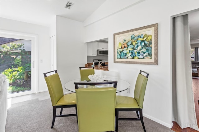 carpeted dining space with vaulted ceiling and sink