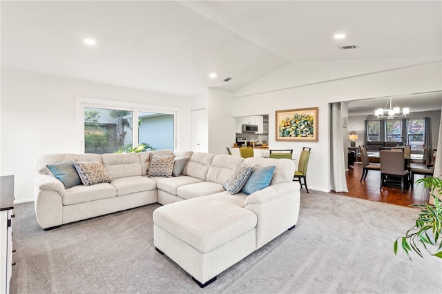 living room featuring hardwood / wood-style floors, vaulted ceiling, and an inviting chandelier