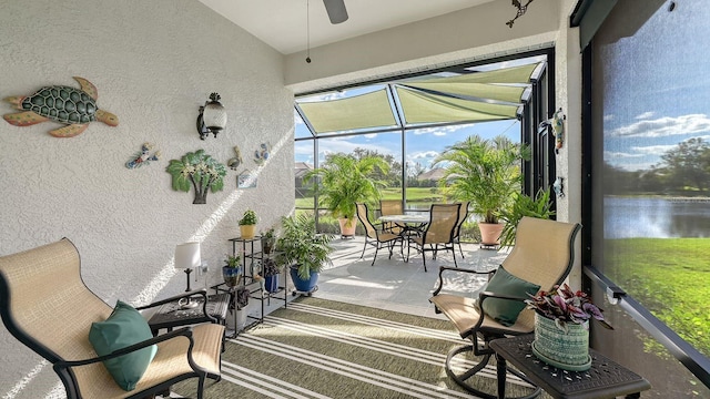 sunroom featuring ceiling fan and a water view