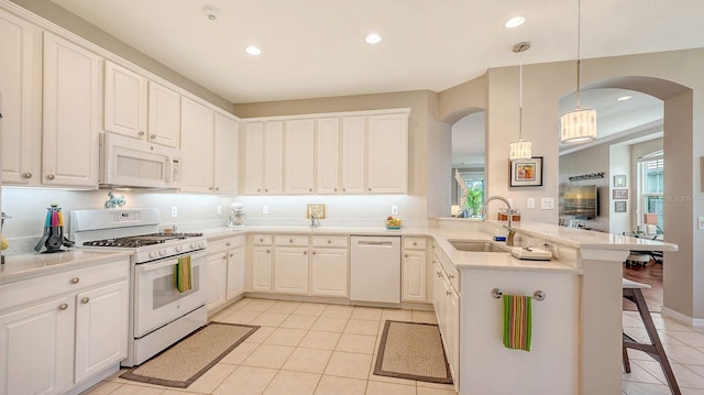 kitchen with kitchen peninsula, a kitchen breakfast bar, pendant lighting, white cabinetry, and white appliances