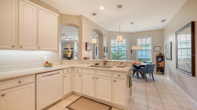 kitchen featuring dishwasher, kitchen peninsula, sink, light tile patterned floors, and decorative light fixtures