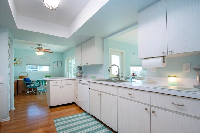 kitchen with kitchen peninsula, white dishwasher, sink, light hardwood / wood-style flooring, and white cabinetry