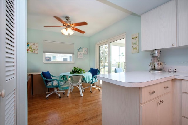 kitchen with kitchen peninsula, light brown cabinetry, light wood-type flooring, and ceiling fan