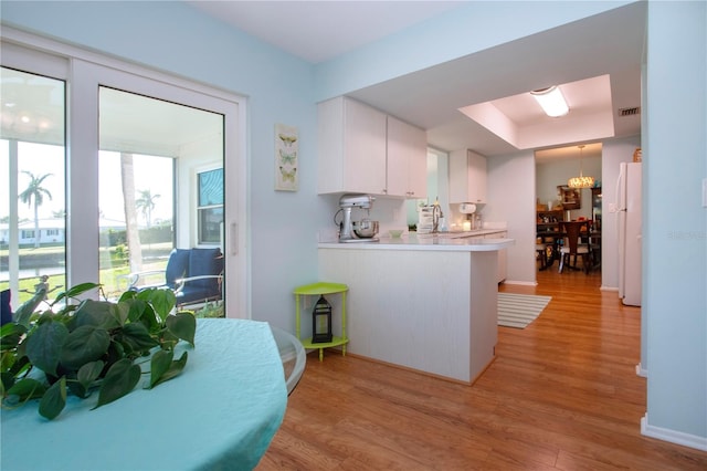 kitchen featuring white cabinets, light hardwood / wood-style floors, kitchen peninsula, and white refrigerator