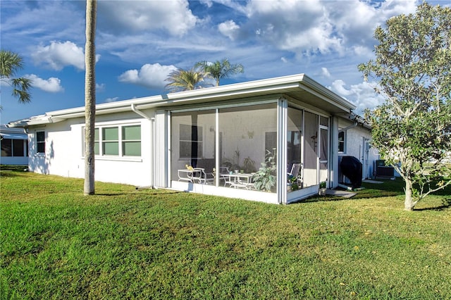 rear view of property with a sunroom, a yard, and central AC unit