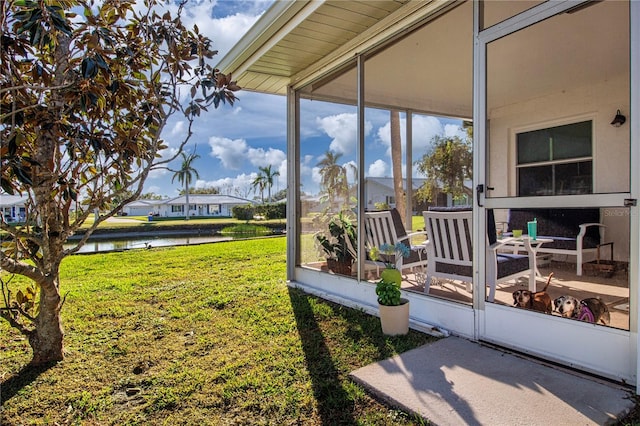 view of yard with a sunroom and a water view