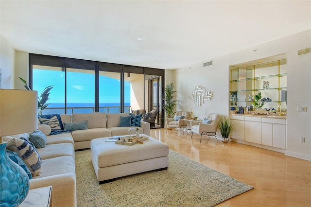 living room featuring a water view, floor to ceiling windows, and light hardwood / wood-style flooring